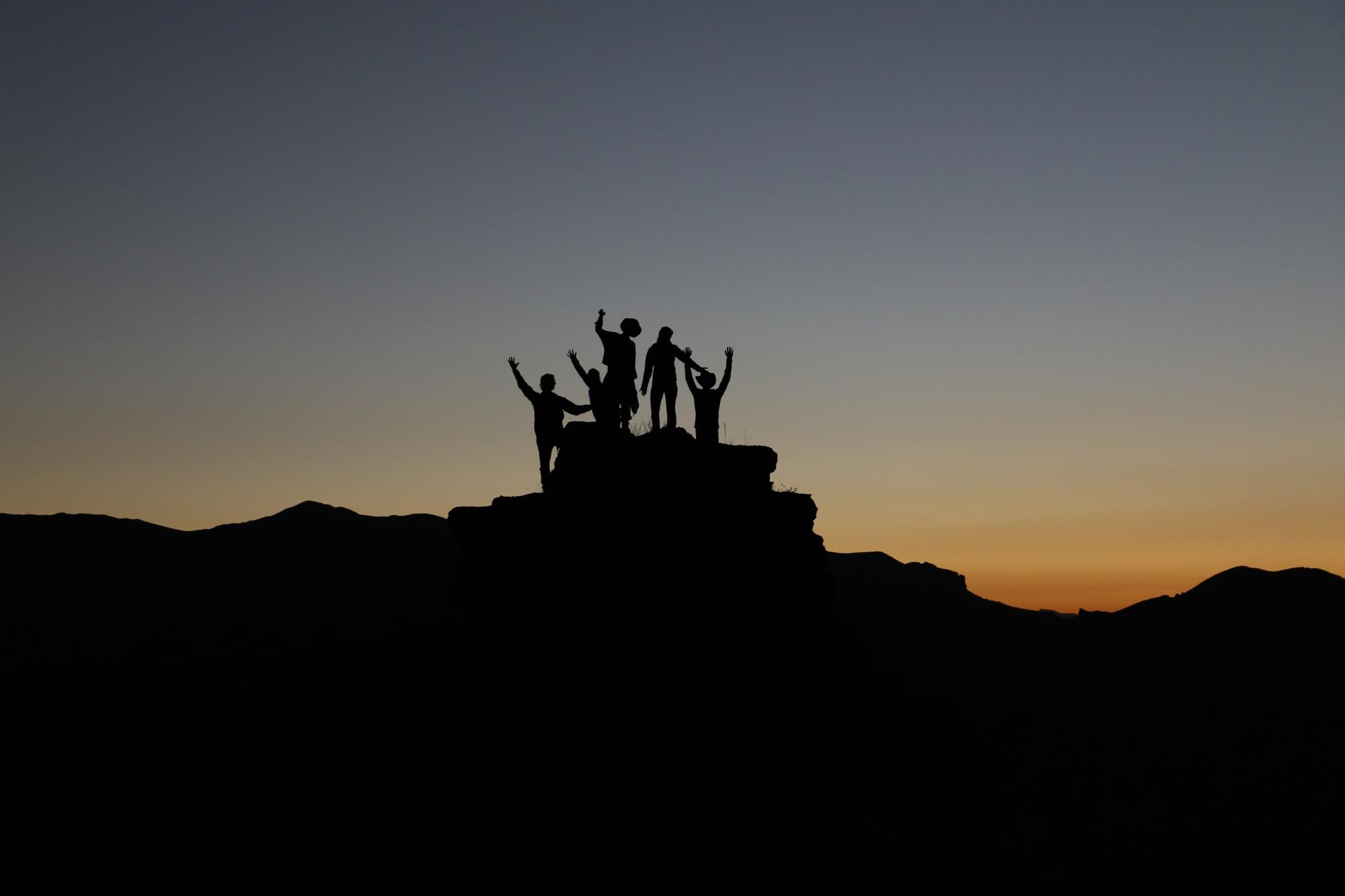Silhouette of people posing on top of a rocky landscape