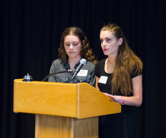 Two students speak at a podium