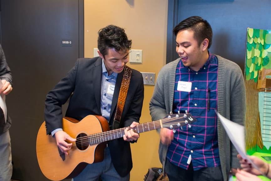 A student plays a guitar while another watches